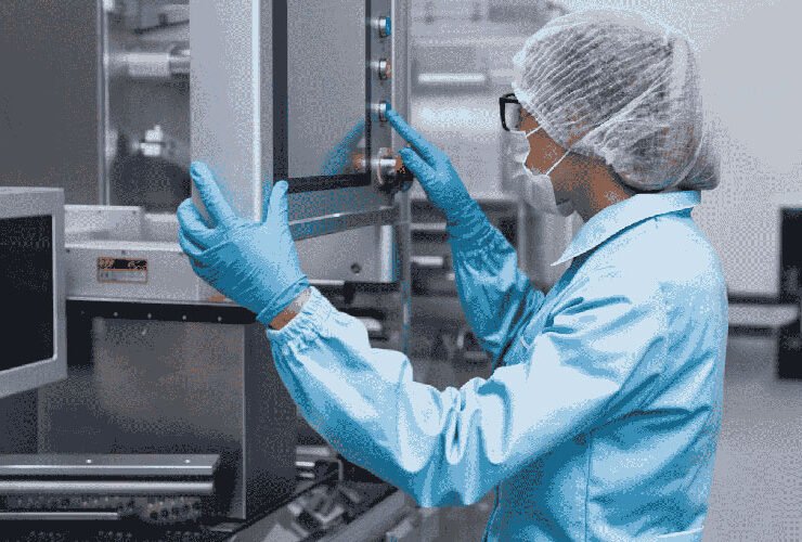 Technician in cleanroom clothing operating testing equipment